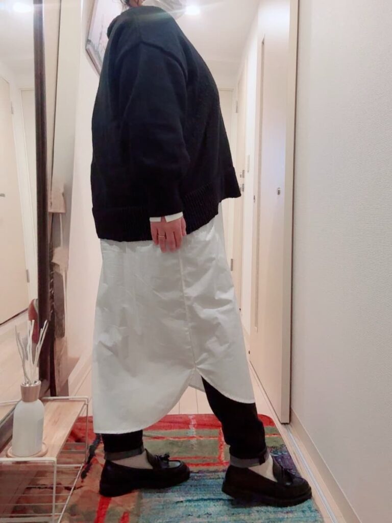 横から見たモノトーンコーデ。サイドのシルエットとラウンドヘムのシャツが腰回りをカバーしている様子