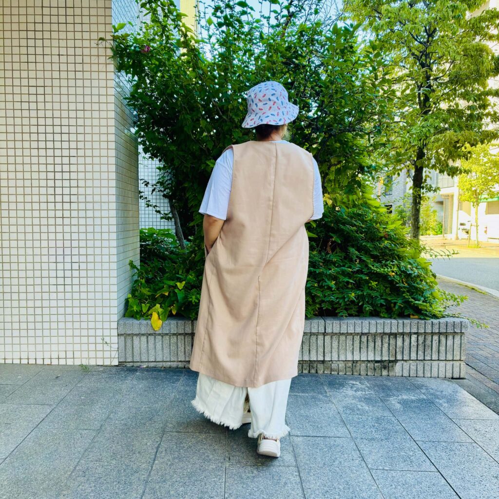 ベージュのジレとロングスカートで合わせたカジュアルな後ろ姿のコーデ